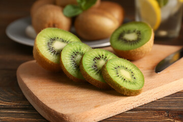 Board with slices of fresh kiwi on wooden background, closeup