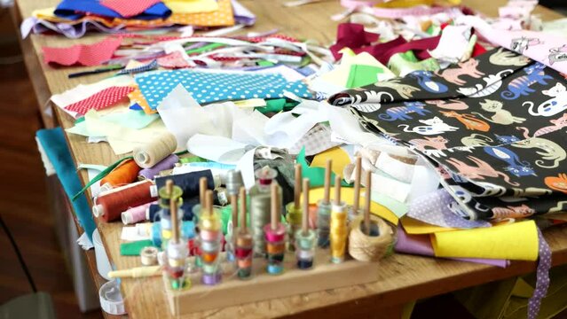 Colorful spools of thread, scraps of fabric scattered on table in game factory.