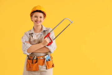 Young female carpenter with hacksaw on yellow background. Labor Day celebration