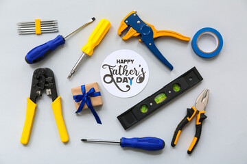 Tools, gift box and greeting card with text HAPPY FATHER'S DAY on grey background