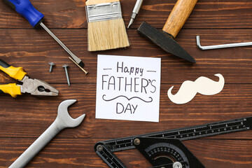 Tools, mustache and greeting card with text HAPPY FATHER'S DAY on wooden background