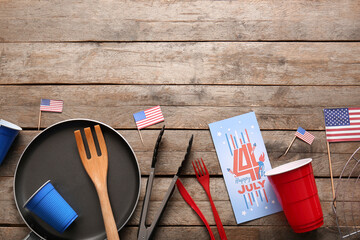 Composition with greeting card for Independence Day celebration and dinnerware on wooden background
