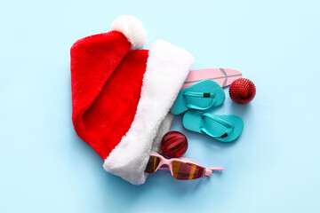 Composition with Santa hat, Christmas balls and beach accessories on color background