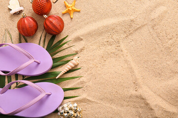 Composition with flip-flops, palm leaf and Christmas decorations on sand