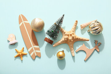 Composition with Christmas decorations, mini surf board and starfishes on color background