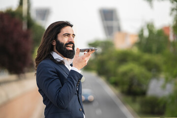Dynamic Businessman Using Voice Assistant on Smartphone Outdoors