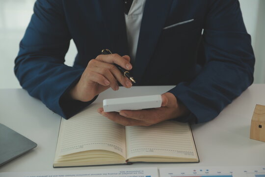 Businessmen holding pens, signing home titles with insurance, care about real estate services and the idea of real estate agents offering interest in installments to their customers.