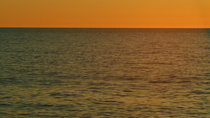 Fototapeta premium Beautiful Sunset Above Sea. Sunrays Flickering In Ripples On Water Surface. Natural Sky Reflects In Sea Warm Colors. Slow motion.