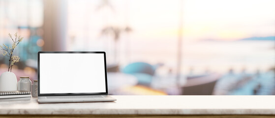 A laptop mockup on a tabletop with a blurred background of a beachfront hotel lounge or restaurant.