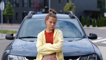 Camera moving to beautiful young teen girl standing in front of car on street looking at camera....