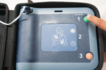 pressing the AED power button to turn it on and use a patient in cardiac arrest