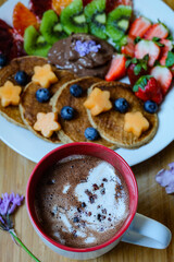 Chocolate raw cacao hot drink and banana pancakes made with roll oats, soy milk, banana  topping with fresh fruit and honey 