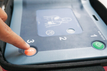 pressing the AED's shock button to deliver an electric shock to a heart attack patient