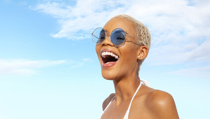 Happy young laughing woman at the beach side, wearing sunglasses, portrait of African latin...