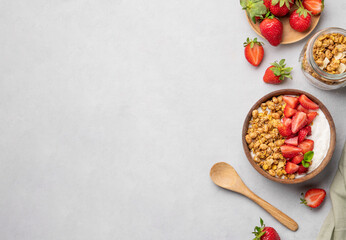 Natural yogurt with granola and strawberries in a wooden bowl on a light background with fresh...