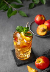 Refreshing peach iced mint tea. The concept of a healthy homemade cold summer drink in a tall glass...
