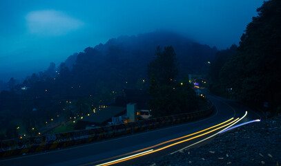 colorful night light trails on road with forest background in puncak bogor Indonesia