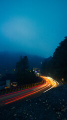 colorful night light trails on road with forest background in puncak bogor Indonesia