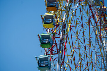 Ferris Wheel Over Blue Sky. Multicolored booths of a Ferris wheel over a blue sky.