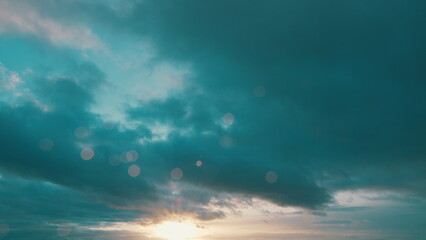 Sun below the horizon and clouds in the fiery dramatic sky. Clouds illuminated by sunbeams.