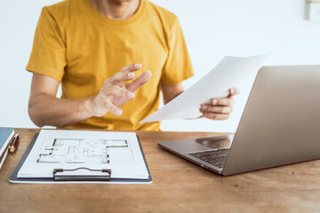 Close up man in yellow T-shirt working at desk. Automobile agreement and insurance documents. Legal...