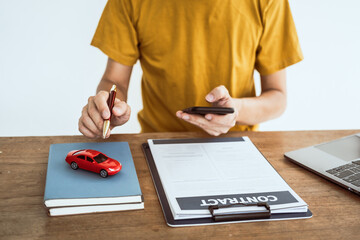 Close up man in yellow T-shirt working at desk. Automobile agreement and insurance documents. Legal investment strategy for auto protection. Crash liability, expense, risk management for success.