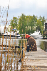 Fototapeta premium a man sits on a wooden pier on a river in the country