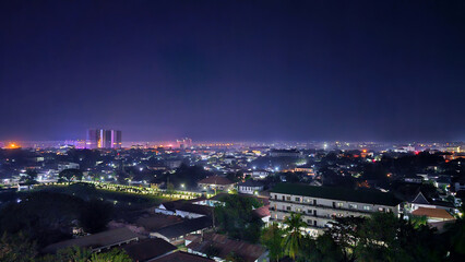 Nighttime view of a cityscape illuminated by lights, featuring a wide-angle perspective that captures the vibrant life and color of the urban environment after dark