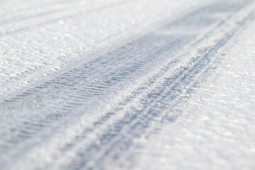 Tire tracks on an icy frozen road, close up. Winter season, slippery road, dangerous for driving