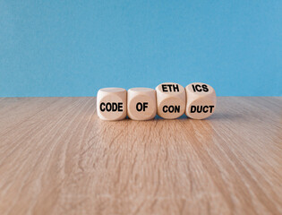 Cubes form the expression 'code of conduct' and 'code of ethics'. Beautiful blue background, wooden...