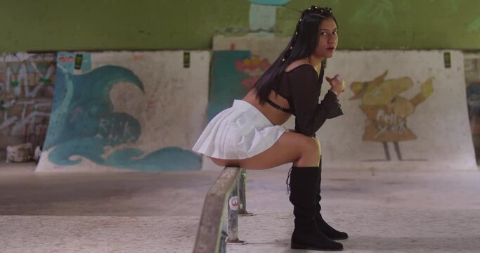 A mini-skirted Hispanic girl explores the indoor skatepark with style.