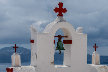 Santorini, Greece, May 5, 2024. Oia. Traditional white bell tower of church with red crosses facing...