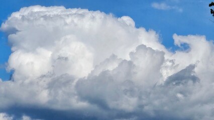 A large cloud in the sky with a blue sky behind it