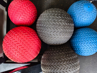 Various rubber slam balls of different sizes on the mat at the gym. Also known as dead ball.
