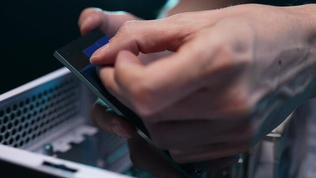 Professional technician engineer male removing protective film from SSD before installing on motherboard, slow motion. Solutions services electronic hardware. Technology chip equipment repair.