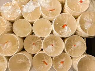 Close-up view of multiple stacks of disposable paper cups, each bundle wrapped in transparent...