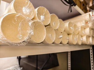 Close-up view of multiple stacks of disposable paper cups, each bundle wrapped in transparent plastic, stored in a restaurant's supply room.