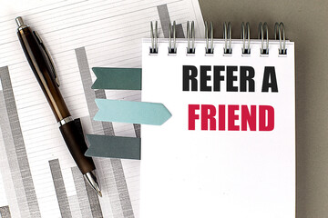 REFER A FRIEND text on notebook with chart on gray background