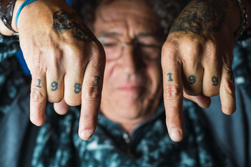 Tattooed man doing rock symbol with hands