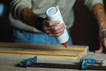 Carpenter gluing wooden board in workshop