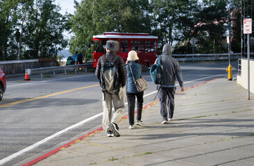 Tourists walking on the  pedestrian sidewalk towards Resolution Park. Tour bus and cars on the...