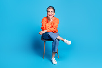 Full body photo of lovely senior lady sit chair minded dressed stylish orange garment isolated on...