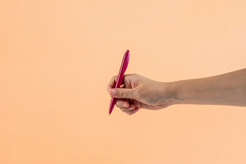 Red plastic pen in hand. Isolated on cream background