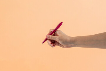 Red plastic pen in hand. Isolated on cream background