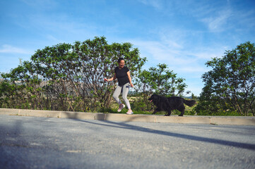 Obraz premium Full length authentic portrait of a cheerful woman running with her pet on leash, as perfect way to walk a dog and to exercise outdoors