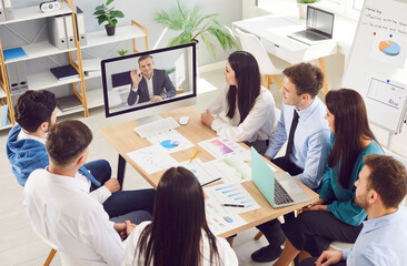 Group of business people having online videoconference in meeting room with man colleague sitting...