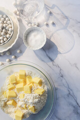 butter, wheat flour, salt, cold water, reusable pie weights basic puff pastry ingredients on white marble background.