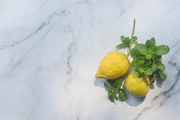 organic lemon with fresh mint leaves on white marble background.