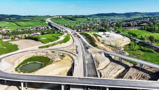New fragment of highway under construction on Zakopianka road, Poland, over Klikuszowa village with a high viaduct, entrance and exit ramps and a traffic circle. State in May 2024. Aerial 4K video