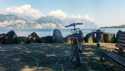 Scenic lakeside rest with bicycle and bench at lake garda - obrazy, fototapety, plakaty